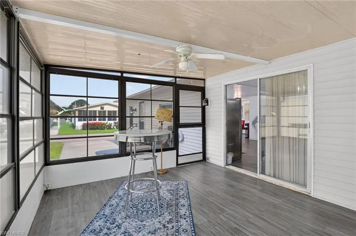 Enclosed patio featuring expansive windows, wood-finish flooring, a ceiling fan, and sliding glass door access