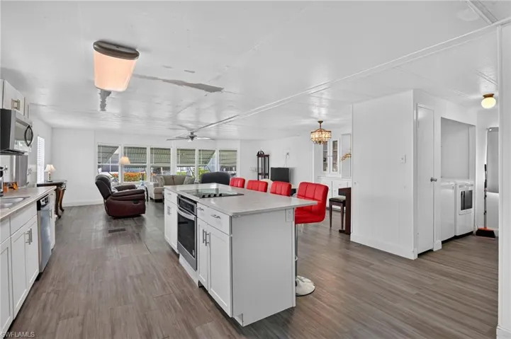 Kitchen island with a built-in cooktop and oven, white cabinetry, and light-toned countertops