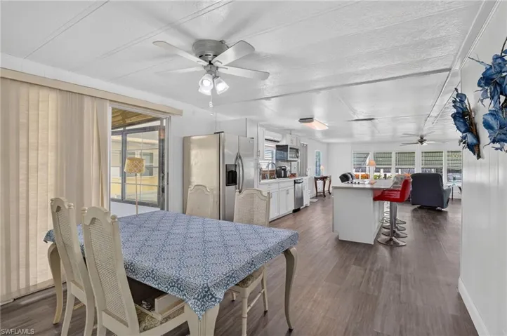Open-concept interior featuring wood-finish flooring, white paneling, and a kitchen island with seating