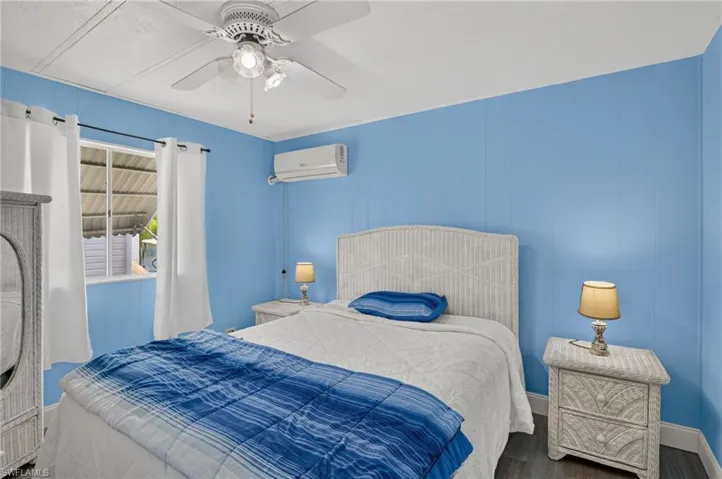 Room featuring wood-finish flooring, a ceiling fan with integrated lighting, and a wall-mounted mini-split air conditioning unit
