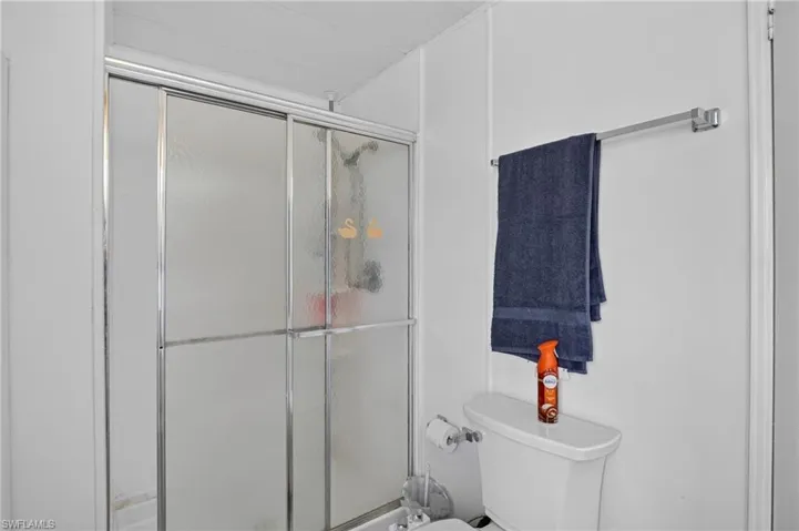 Bathroom featuring a shower with sliding frosted glass doors, a white toilet, and a wall-mounted towel bar