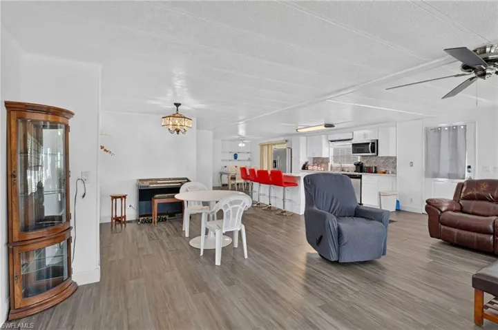 Open-concept living area featuring wood-finish flooring, white walls, and a ceiling fan