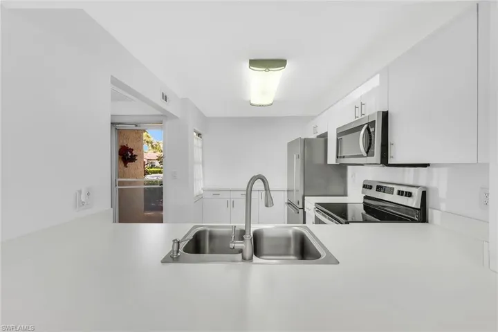 Kitchen featuring light countertops, appliances with stainless steel finishes, and white cabinetry
