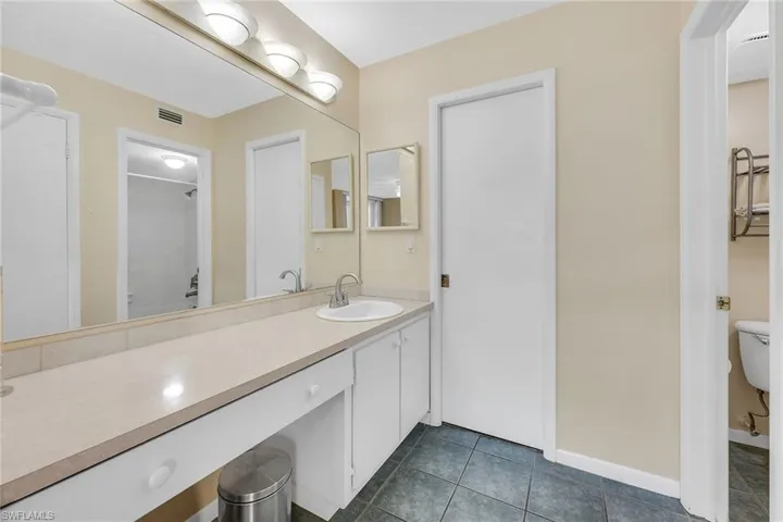 Bathroom with a shower, vanity, and dark tile patterned floors