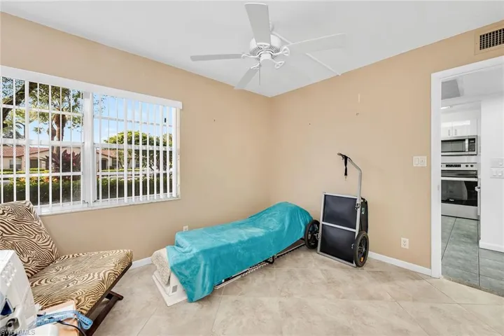 Tiled bedroom featuring a ceiling fan and baseboards