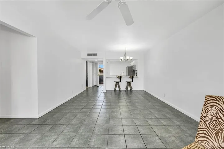 Unfurnished living room featuring tile patterned flooring, a chandelier, and ceiling fan
