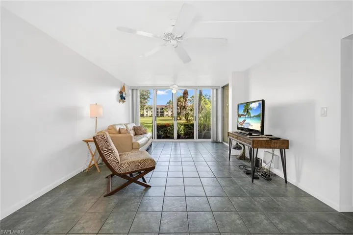 Sitting room featuring a wall of windows, dark tile patterned floors, and ceiling fan