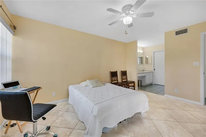 Bedroom featuring light tile patterned flooring, a desk, and ceiling fan