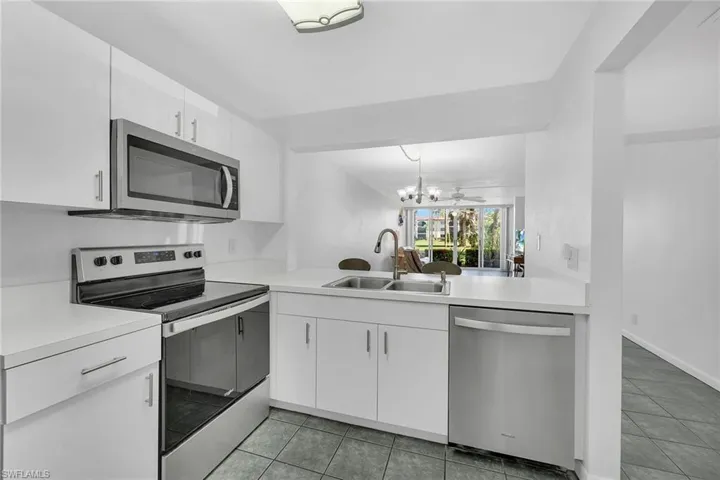 Kitchen featuring stainless steel appliances, light countertops, white cabinets, and light tile patterned flooring