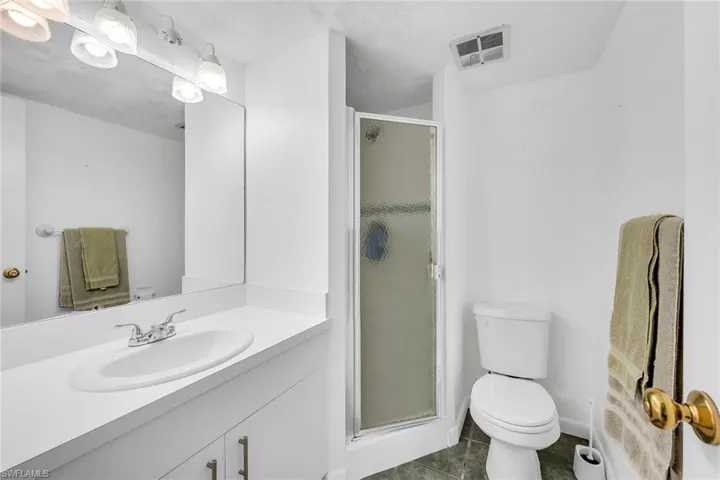 Bathroom with a stall shower, vanity, and dark tile patterned flooring