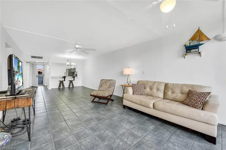 Living room with dark tile patterned floors, ceiling fan, and a chandelier