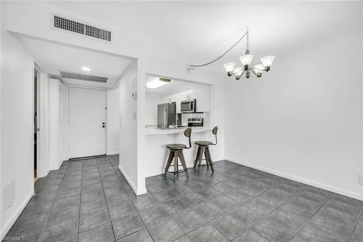 Kitchen with light countertops, a kitchen bar, a peninsula, appliances with stainless steel finishes, and white cabinets