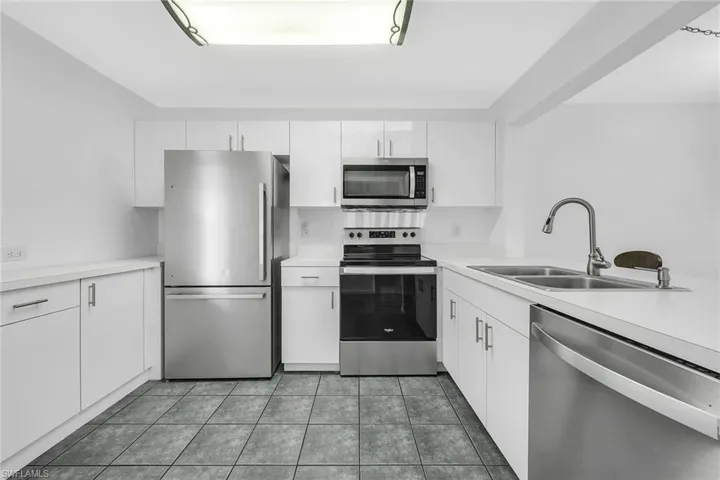 Kitchen featuring appliances with stainless steel finishes, light countertops, white cabinetry, and light tile patterned flooring