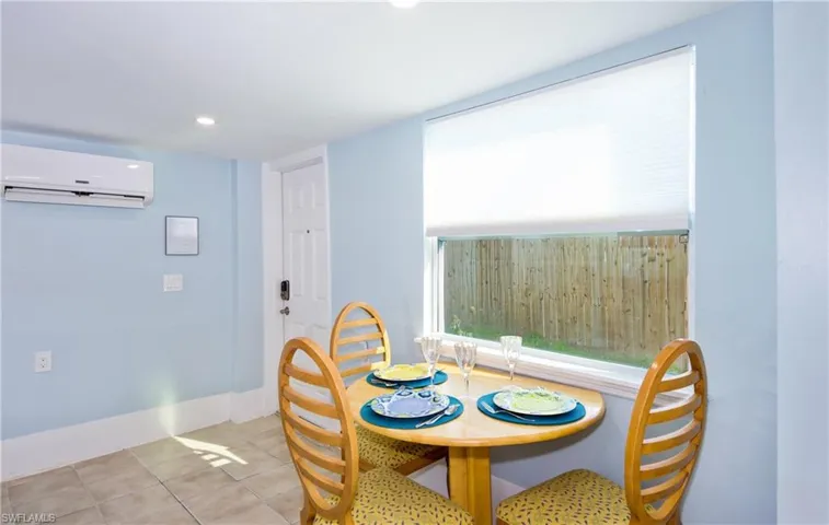 Dining area with light tile patterned flooring, an AC wall unit, and recessed lighting - Virtually Edited Image