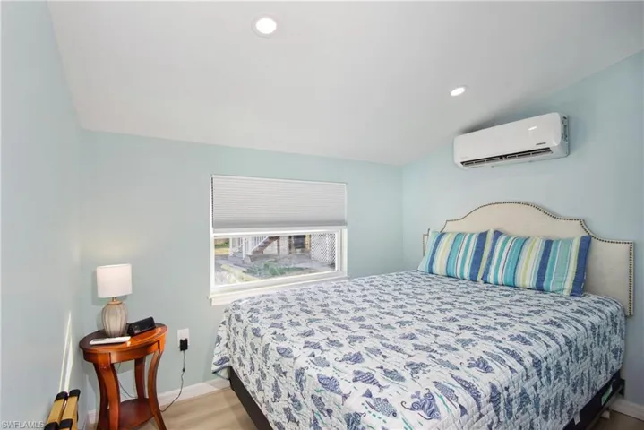 Bedroom with recessed lighting, vaulted ceiling, light wood-style flooring, and a wall mounted AC - Virtually Edited Image
