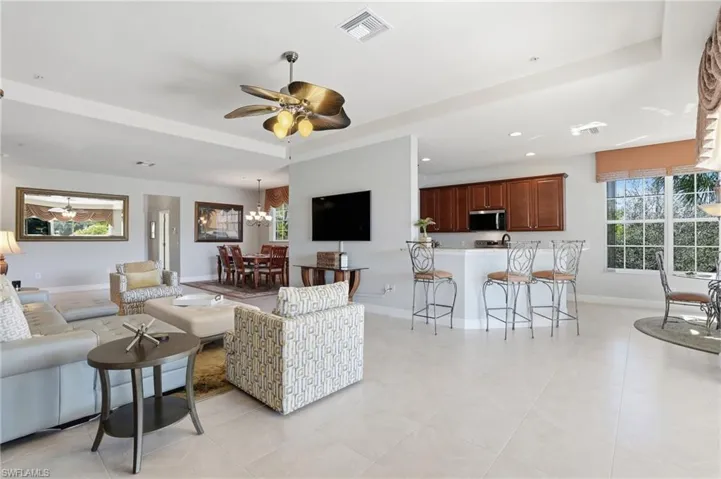Living area featuring ceiling fan, suspended lighting, and a raised ceiling