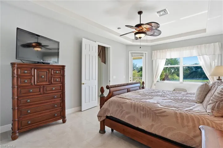 Bedroom with access to outside, a ceiling fan, and a tray ceiling