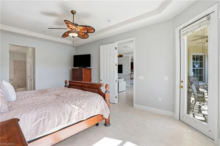 Bedroom featuring a ceiling fan, connected bathroom, access to outside, and a tray ceiling