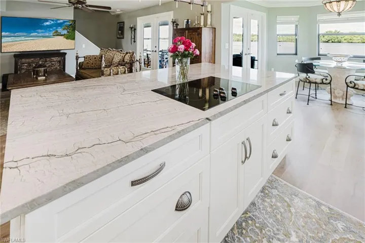 Kitchen featuring french doors, white cabinets, light stone counters, black electric stovetop, and crown molding