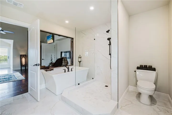 Bathroom with marble look tile flooring, a freestanding bath, a marble finish shower, recessed lighting