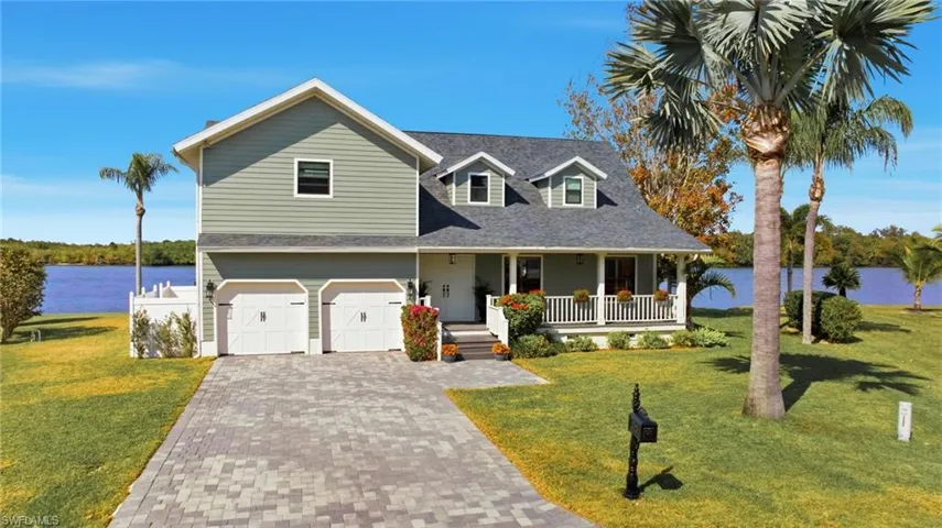 View of front of home featuring a water view, covered porch, a front lawn, and a garage