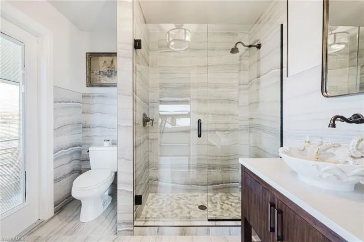 Bathroom with a shower stall, tile walls, and vanity