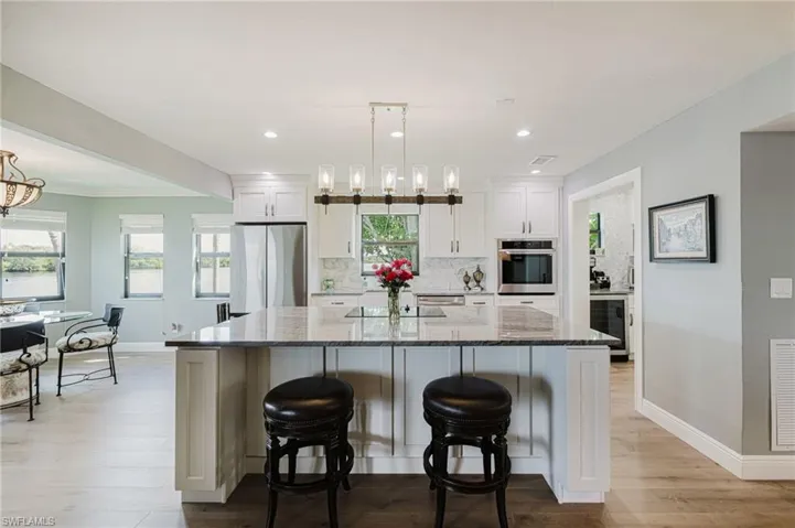 Kitchen with white cabinetry, light stone counters, a breakfast bar, decorative light fixtures, and recessed lighting