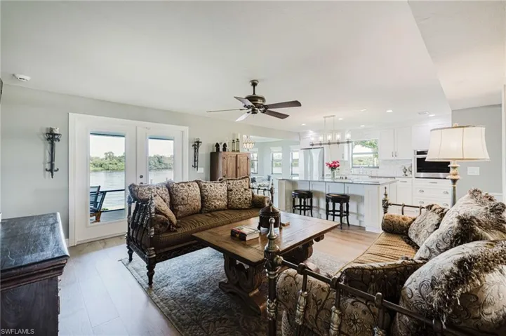 Living area with light wood flooring, french doors, a ceiling fan, and a water view
