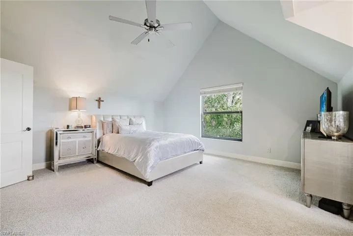 Bedroom with light colored carpet, lofted ceiling, and a ceiling fan