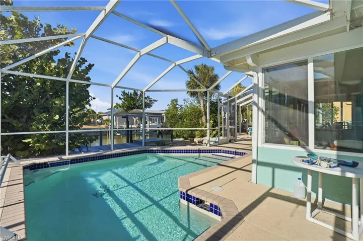 Swimming pool with a sunroom, a patio area, and a lanai - Virtually Edited Image