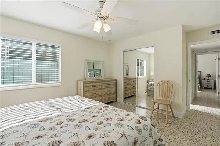 Bedroom with dark speckled floor, a closet, and ceiling fan - Virtually Edited Image