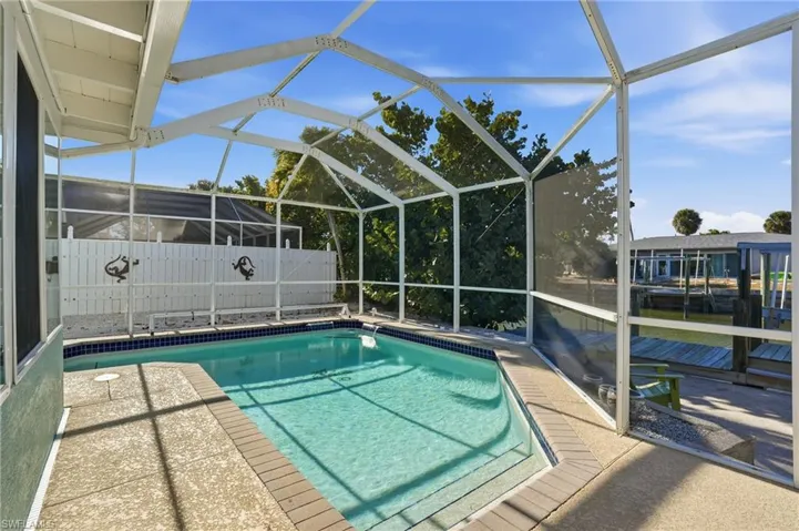 View of pool with a lanai, a sunroom, and patio surround - Virtually Edited Image