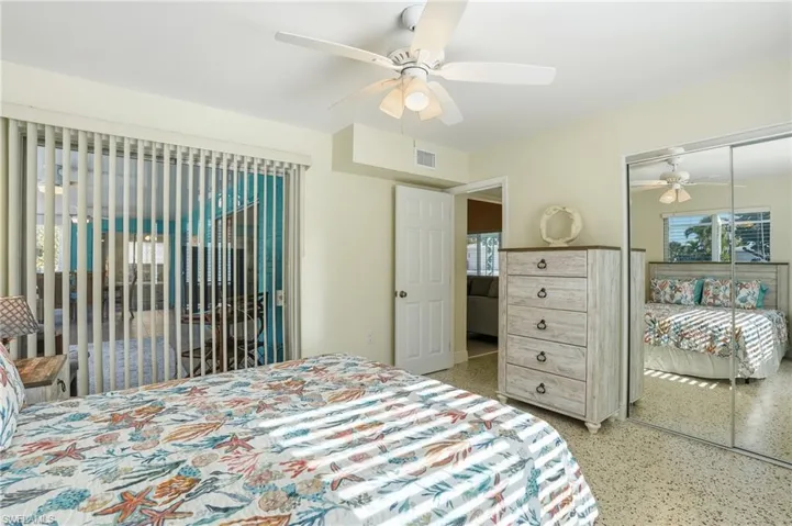 Bedroom featuring a ceiling fan, access to outside, dark speckled floor, and a closet - Virtually Edited Image