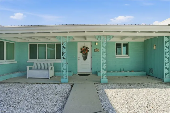 View of exterior entry featuring a metal roof and covered porch - Virtually Edited Image