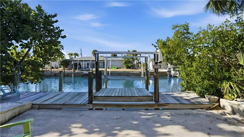 Dock area featuring a water view and boat lift - Virtually Edited Image
