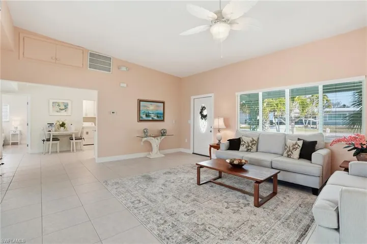 Living area featuring ceiling fan, washer / dryer, light tile patterned floors, and lofted ceiling - Virtually Edited Image