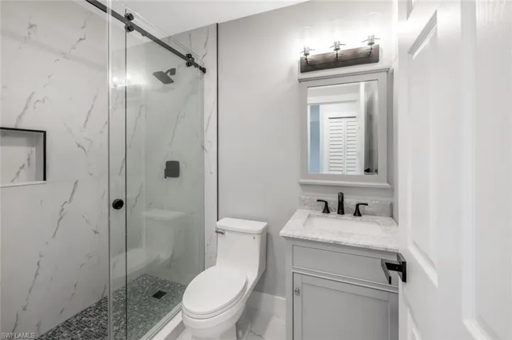 Bathroom featuring a marble finish shower, vanity, and toilet