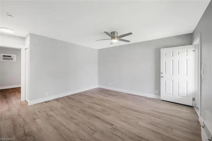 Empty room with baseboards, a ceiling fan, wood finished floors, and a wall mounted AC