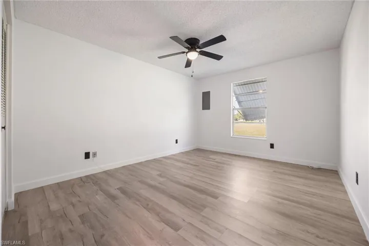 Unfurnished room with light wood-style floors, a textured ceiling, and a ceiling fan