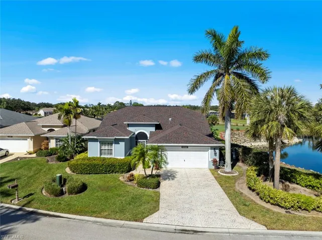 Ranch-style house with a garage, a front lawn, and a water view