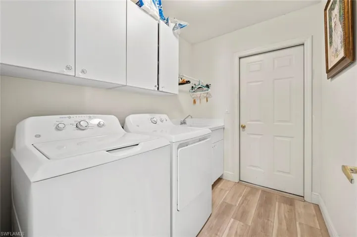 Washroom with separate washer and dryer, sink, cabinets, and light wood-type flooring