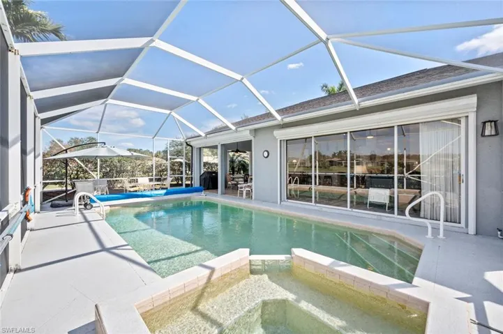 View of pool featuring an in ground hot tub, area for grilling, a patio, and glass enclosure