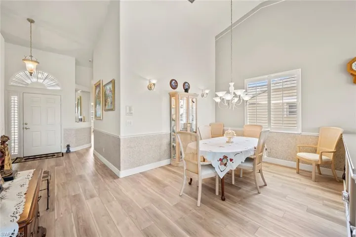 Dining area with high vaulted ceiling, a notable chandelier, and light hardwood / wood-style floors