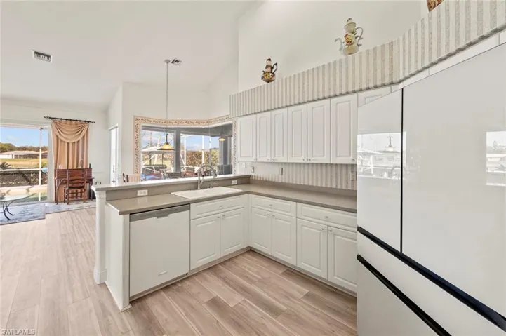 Kitchen with sink, white cabinetry, light hardwood / wood-style flooring, dishwasher, and kitchen peninsula