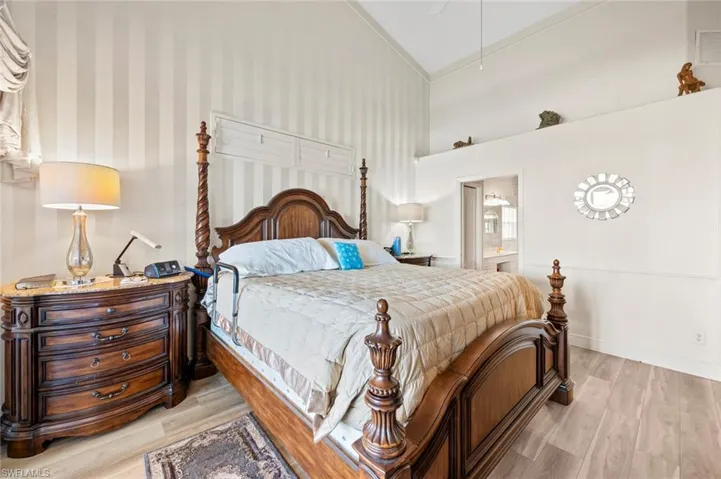 Bedroom featuring connected bathroom, light hardwood / wood-style flooring, and high vaulted ceiling