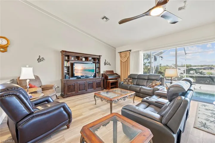 Living room featuring ceiling fan, lofted ceiling, and light hardwood / wood-style floors