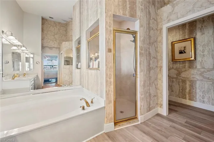 Bathroom with hardwood / wood-style flooring, vanity, and plus walk in shower