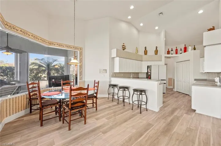 Dining space with sink, high vaulted ceiling, and light hardwood / wood-style floors