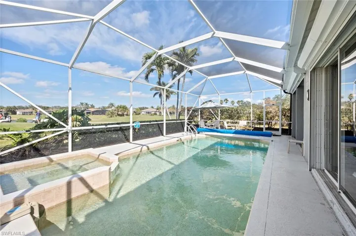 View of swimming pool featuring an in ground hot tub, glass enclosure, and a patio