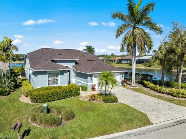 View of front facade with a garage, a water view, and a front lawn